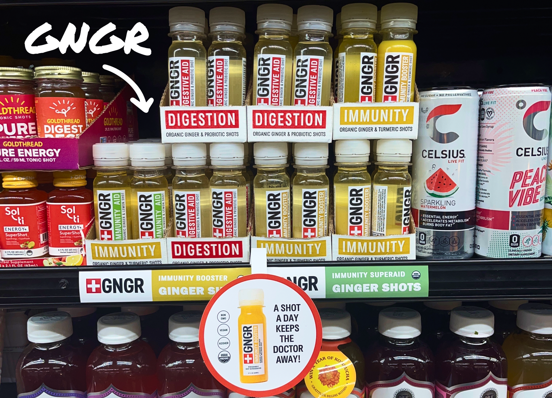 GNGR ginger shots for Digestion and Immunity on a grocery shelf, with a sign saying "A shot a day keeps the doctor away!.