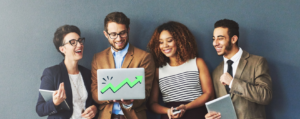 Four business professionals smile by a gray wall - Shopify Plus Alternatives