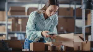 Woman in striped shirt snaps photo of open box - Cin7 Alternatives